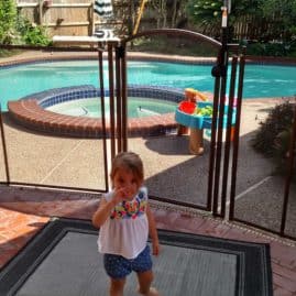 little girl standing next to fence gate